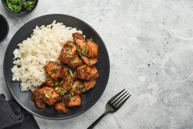 Baharatlı teriyaki tavuğu pirinçli fileto, yeşil soğanlı ve siyah susam tohumlu gri levha, taş ya da beton zemin üzerinde. Kopyalama alanı olan üst görünüm.