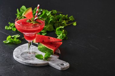 Naneli ve buzlu bir bardak karpuzlu Margarita kokteyli. Yaz, siyah masada bardaklarla içecekleri tazeler. Sağlıklı yaz yemekleri kavramı.