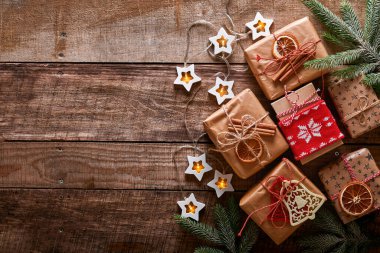 Noel ya da yeni yıl arkaplanı köknar dalları, çelenkler, Noel baloları, hediye kutuları, tahta kar taneleri ve karanlık ahşap arka planda yıldızlar. Metnin için yer