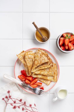 Tatil için geleneksel yemek Maslenitsa. Ballı ince krep, taze çilek ve kahvaltı hazırlamak için malzemeler. Üst görünüm