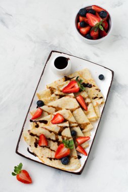 Çikolata soslu ev yapımı krep, güzel beyaz seramik tabakta kahvaltıda taze çilek ve bal. Mesaj ya da tarif için boşluk. Üst görünüm