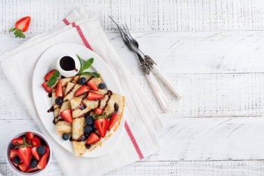 Çikolata soslu ev yapımı krep, güzel beyaz seramik tabakta kahvaltıda taze çilek ve bal. Mesaj ya da tarif için boşluk. Üst görünüm