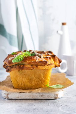 Basit bir açık gri beton masada fesleğen yapraklarıyla süslenmiş ev yapımı pesto ekmeği. İtalyan geleneksel ekmeği. Uzayı kopyala Üst görünüm.