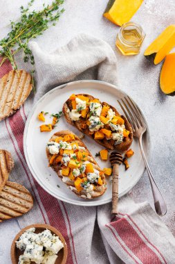 Fırınlanmış balkabağı sandviçi, mavi küflü Dorblu peynirli, bal ve kekik, beton, eski, aydınlık arka planda. Üst görünüm