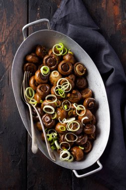 Soya sosunda kızartılmış mantar şampiyonu, biberli ve eski bir masada eski bir metal kasede buğulanmış soğan. Seçici odak