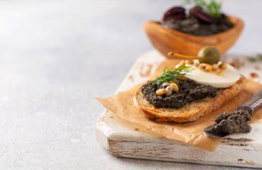 Bir dilim mozzarella peynirli sandviç ve tapenade, açık gri kırsal masa arka planında kapari. Geleneksel Provence yemeği. Seçici odak
