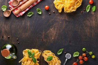 Tagliatelle. Ev yapımı makarna, fesleğen yaprağı, un, biber, zeytinyağı, vişneli domates ve siyah ahşap arka planda merdane ve makarna bıçağı. Yemek konsepti. Model yap. Kopyalama alanı ile yatay.