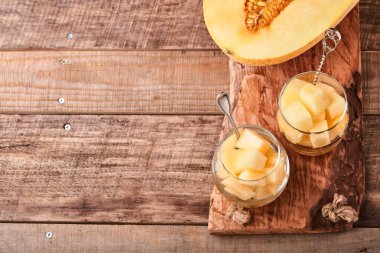 Kavun. Eski ahşap arka planda cam içinde meyve tatlısı yapmak için taze kavun parçaları. Model yap. Üst görünüm.