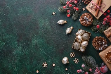 Noel ağacı dalları, Noel baloları, hediye kutuları, ahşap kar taneleri ve yeşil betondan arkaplan yıldızları Noel kutlamalarınız için. Kopyalama alanı olan üst görünüm. Noel tebrik kartı..