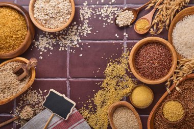 Beyaz, kahverengi ve kırmızı pirinç, karabuğday, darı, mısır hokeyi, kinoa ve bulgur kahverengi taştan mutfak masasında. Glütensiz mısır gevreği. Kopyalama alanı olan üst görünüm