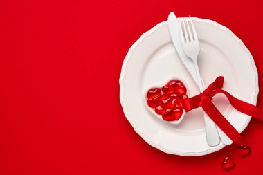 Sevgililer Günü arkaplanı ya da boş pembe tabak ve kırmızı arka planda beyaz yazılımla konsept. Üst görünüm düzlüğü kopyalama alanı ile yatıyordu.