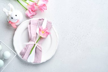 Gri masa üzerinde çiçek dekoru olan Paskalya sofrası. Zarif bir akşam yemeği. Model yap. Üst görünüm.