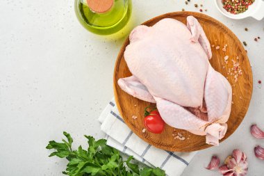 Mutfakta gül biberi, limon, kekik, sarımsak, vişneli domates, sorrel ve tuz yapımında kullanılan malzemelerle dolu çiğ tavuk açık gri kayrak, taş veya beton zemin üzerinde. Üst Manzara. Boşluğu kopyala