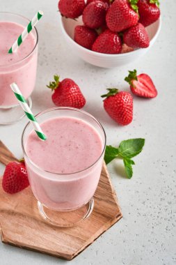 İki çilekli smoothie ya da böğürtlenli milkshake ve açık pembe arka planda nane şekeri. Yaz içeceği, milkshake ve ferahlatıcı organik konsept. Sağlıklı beslenme, vejetaryen gıda konsepti.