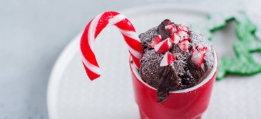 Yeni yıl çikolatalı keki mikrodalga fırında, fincanda, klasik gri arka plan dokusuyla pişirildi. Üst Manzara. Yeni yıl kartı.