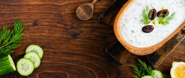 Geleneksel Yunan sosu Tzatziki zeytin ağacından yapılmış kasede eski bir köy arka planında. Üst görünüm.