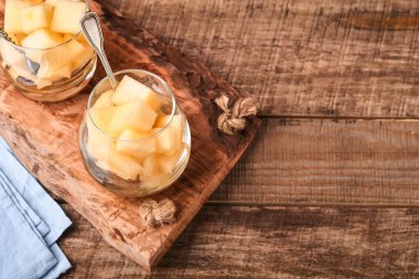 Kavun. Eski ahşap arka planda cam içinde meyve tatlısı yapmak için taze kavun parçaları. Model yap. Üst görünüm.