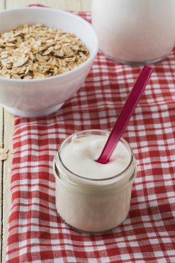 Güler yüzlü dondurulmuş kırmızı meyveler, süt ve yulaf ezmesi bir gözlük ile ahşap arka planda yaptı. Seçici odak.