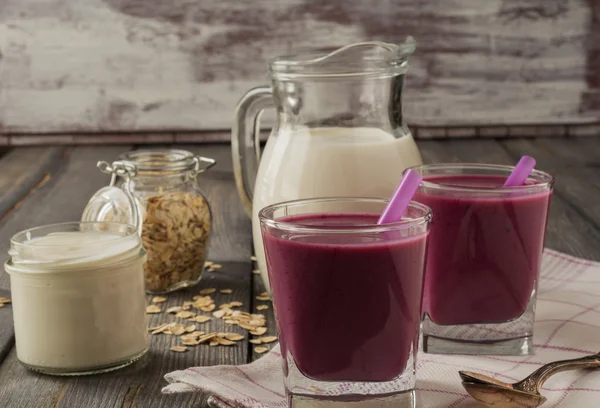 Smoothie feito com bagas vermelhas congeladas, leite e aveia em um óculos em fundo de madeira.Foco seletivo . — Fotografia de Stock