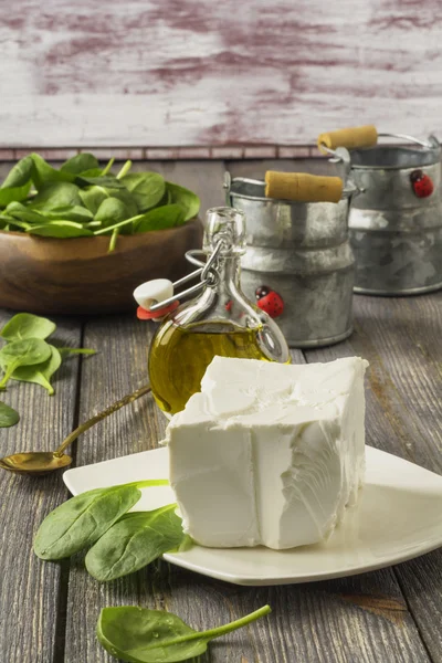 Сыр фета с оливковым маслом и сырым шпинатом на старом столе . — стоковое фото