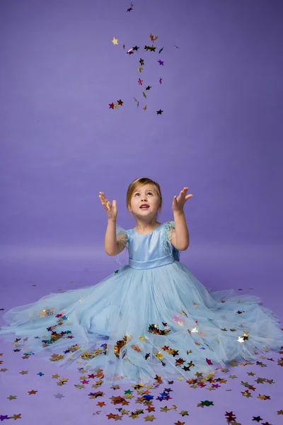 Ein Kleines Mädchen Blauen Prinzessinnenkleid Zaubert Mit Konfetti Auf Lila — Stockfoto