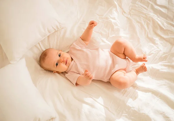 Uma Menina Pequena Bodysuit Rosa Está Deitado Cama — Fotografia de Stock