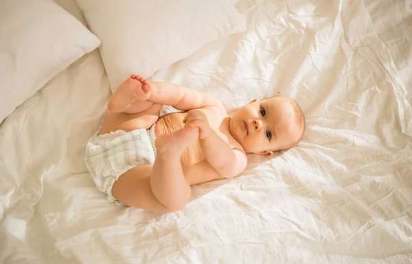 Una Bambina Con Pannolino Sdraia Sul Letto Guarda Telecamera — Foto Stock