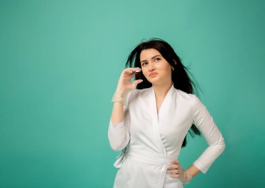 Beyaz takım elbiseli bir güzellik uzmanının elinde yazı için yeri olan turkuaz bir arka plan var.