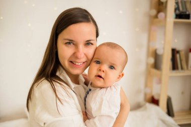 Bir bebeğin anne ve kızının portresi. Sarılmak ve odadaki kameraya bakmak.