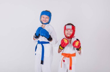 Beyaz kimonolu, kasklı ve eldivenli iki çocuğun portresi beyaz bir arka planda duruyor ve mesaj için yer var.