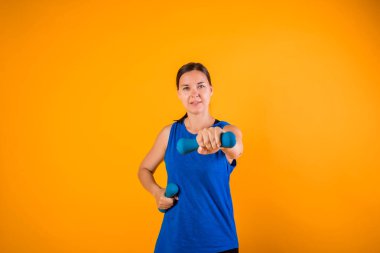 Turuncu arka planda dambılı ve metin için yeri olan sporcu kadın.