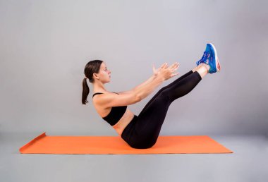 Kadın, gri arka planda Mat 'te basın üzerinde alıştırma yapıyor.