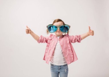 Güzel kız komik gözlüklü, kot pantolonlu ve bluzlu bir kız, kız parmaklarıyla işaret ediyor.