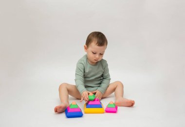 Yeşil elbiseli küçük bir çocuk oturur ve beyaz arka planda bir piramit toplar ve mesaj için bir yeri vardır. Mantık oyunları