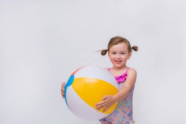 Mayo giymiş gülümseyen küçük bir kız. Beyaz izole bir arkaplanda şişme bir top ve mesaj için yeri var.
