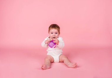 Beyaz elbiseli küçük bir kız oturur ve pembe arka planda üzerinde uzay kopyası olan bir şişe su içer.