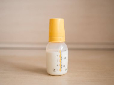 Mutfak masasında bir şişe süt var. Şişede bebek maması.