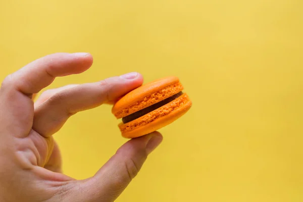 El ele tutuşup sarı arka planda kurabiyeli pasta yiyeceğiz. Turuncu renkli Makaronlar.