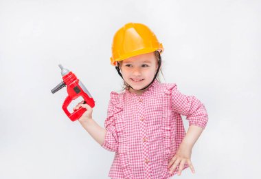 Küçük bir kız inşaatçıyı oynuyor. Elinde tornavidayla turuncu kasklı bir kız..