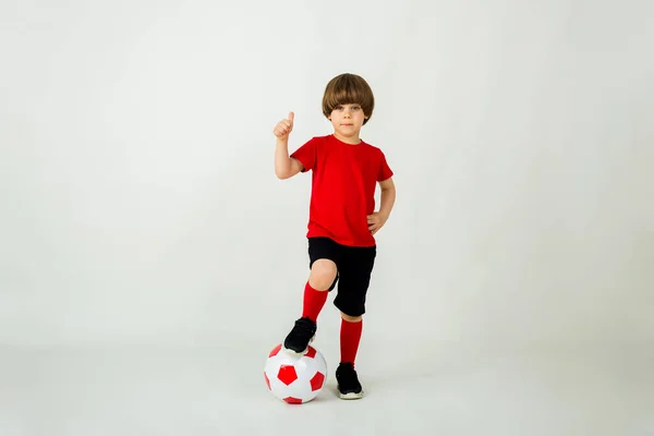 Kırmızı Tişörtlü Şortlu Küçük Bir Çocuk Beyaz Arka Planda Futbol — Stok fotoğraf