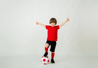 Küçük mutlu futbolcu bir futbol topuyla beyaz bir arka planda duruyor ve mesaj için yer var.