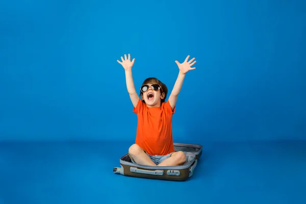 Счастливый Маленький Мальчик Солнечных Очках Сидит Чемодане Синем Фоне Пространством — стоковое фото