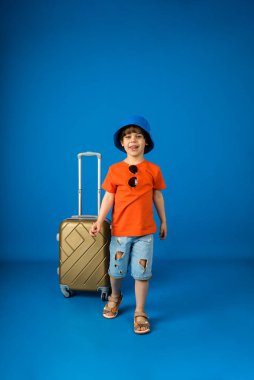 Panama 'da küçük mutlu bir çocuk, mavi bir arka planda bavulu var ve mesaj atmak için yeri var.