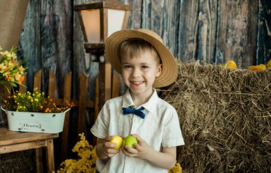 Mutlu küçük beyefendi Paskalya kırsalında renkli yumurtalarla ayakta duruyor.