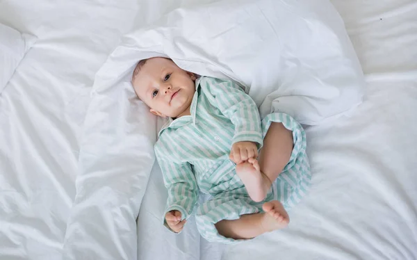 Glad Liten Pojke Randig Pyjamas Ligger Säng Med Vita Sängkläder — Stockfoto