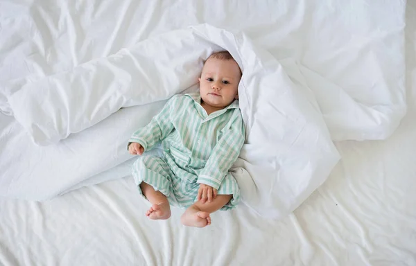 Αγοράκι Τις Ριγέ Πιτζάμες Ξαπλώνει Μια Λευκή Κουβέρτα Στο Κρεβάτι — Φωτογραφία Αρχείου