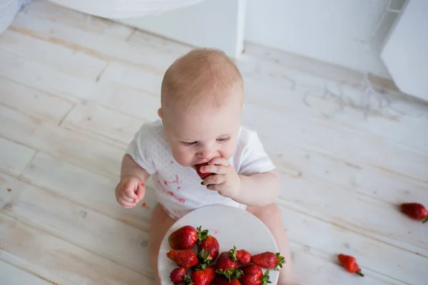 Beyaz arka planda beyaz çilek yiyen beyaz bir çocuk, boşluğun bir kopyasıyla birlikte. Üst görünüm