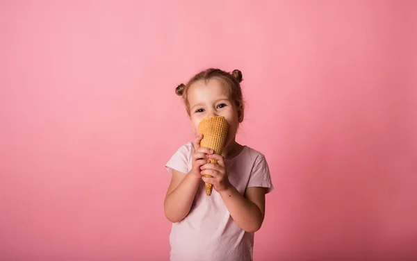Güzel sarışın kız pembe arka planda dondurma külahı yer ve mesaj için yer var.