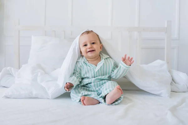 Szczęśliwy Chłopiec Piżamie Paski Siedzi Pod Białym Bawełnianym Kocem Łóżku — Zdjęcie stockowe