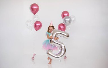 Güzel doğum günü kızı, beyaz şenlik arka planında beş numaralı folyoyu tutuyor.